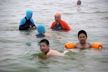 Varios bañistas con 'facekini' en una playa de Qingdao, en la provincia de Shandong, al noreste de China.