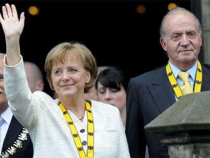 Angela Merkel saluda tras recibir el premio acompañada por el rey Juan Carlos ayer en Aquisgrán.