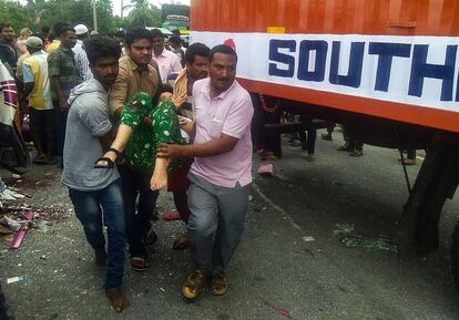 Varios hombres ayudan a trasladar a una mujer herida en el accidente de autobús.