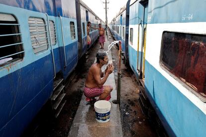 Un hombre se baña entre dos trenes en un caluroso día en Jammu, en India.