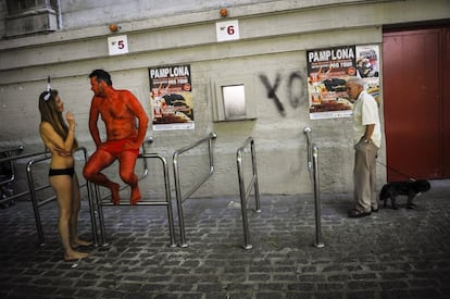 Dos activistas antitaurinos hablan en los exteriores de la plaza de toros ante la mirada de un hombre el día previo al inicio de las fiestas.