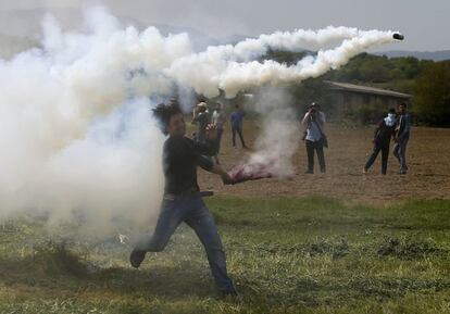 Un refugiado devuelve un bote de humo en un enfrentamiento con la policía en la frontera freco-macedonia, cerca de Idomeni.