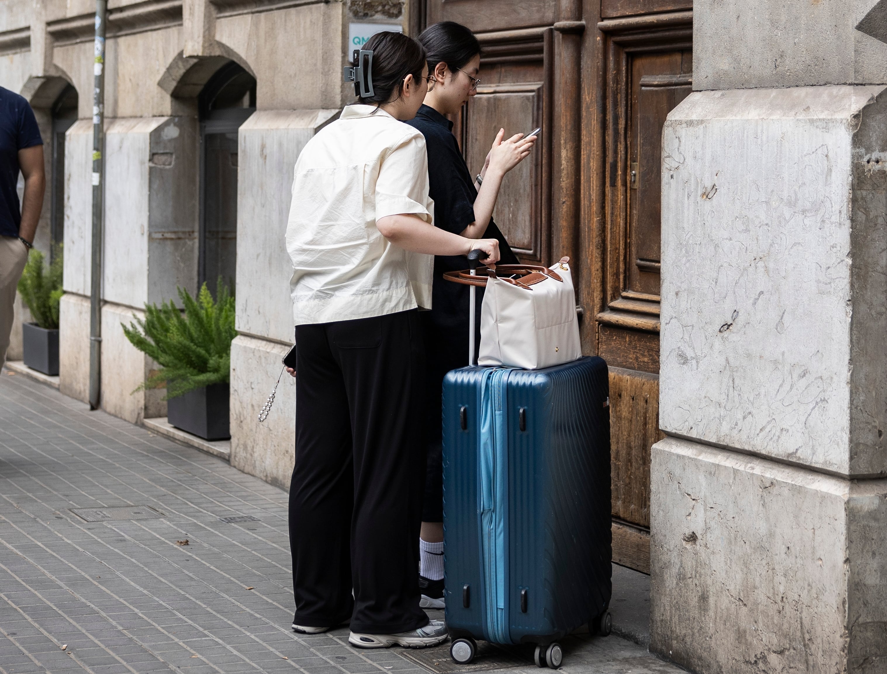 Dos turistas frente a un portal a punto de entrar en un piso turístico en la Calle Roger de Llúria del barrio del Eixample de Barcelona.
