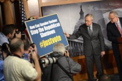 Los senadores demócratas Harry Reid (i) y Charles Schumer (d) muestran un cartel en el que se lee "Cómo puede el presidente de la Cámara de Representantes, (el republicano John) Boehner, parar el "cierre Republicano" durante una rueda de prensa en el Capitolio en Washington DC, Estados Unidos, esta semana.