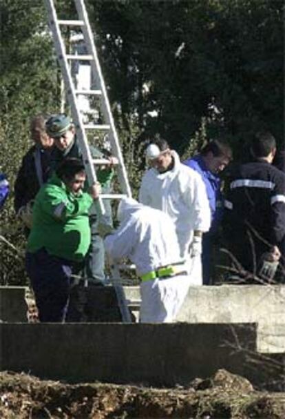 Guardias civiles vestidos de blanco descienden a la fosa séptica.