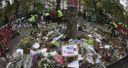 Empleados municipales recogen flores y objetos en memoria de las víctimas ante la sala Bataclan de París.