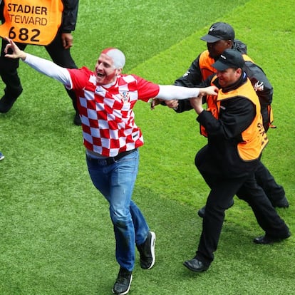 El hincha croata que se coló, más feliz que una perdiz, saluda a las gradas mientras lo sacan de la cancha.  