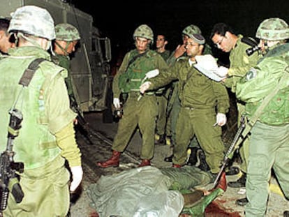 Soldados israelíes rodean el cadáver de una de las víctimas del ataque palestino en Cisjordania.