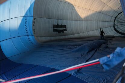 Dentro de la envoltura de uno de los cinco globos, un técnico hace un gesto a su compañero mientras inflan el aerostato.