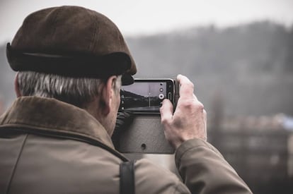 Una persona mayor de 60 años toma una foto con un móvil.