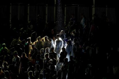 Fans watch in the rain as Brazil's Alison Cerutti and Bruno Oscar Schmidt play Italy's Daniele Lupo and Paolo Nicolai in the men's beach volleyball gold medal match at the 2016 Summer Olympics in Rio de Janeiro, Brazil, Friday, Aug. 19, 2016. (AP Photo/David Goldman)