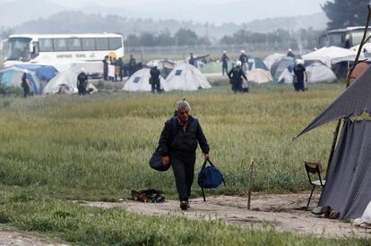 Un migrante lleva sus pertenencias durante el desalojo del campamento de refugiados de Idomeni (Grecia). La policía griega comenzó esta mañana a desalojar el campamento improvisado de Idomeni, en la frontera con Macedonia, donde se encuentran más de 8.400 refugiados.