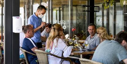Un camarero toma nota a unos comensales en la terraza de un restaurante del Paseo Maritimo de Playa de Aro, Costa Brava (Girona).