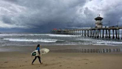 Una surfista junto al muelle de Huntington Beach, en California.