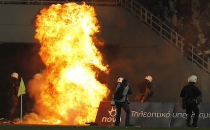 Varios polic&iacute;as intentan extinguir un incendio causado por los hinchas del Panathinaikos.