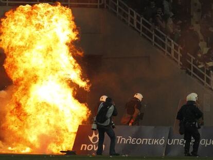 Varios polic&iacute;as intentan extinguir un incendio causado por los hinchas del Panathinaikos.