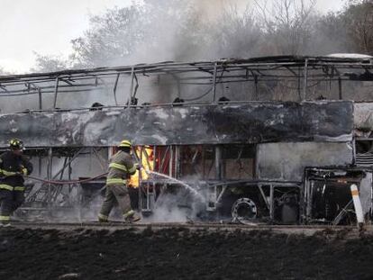 Bombeiros tentam apagar as chamas de um ônibus incendiado em Jalisco.