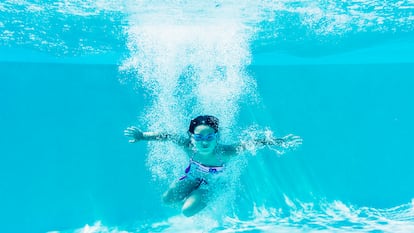 Una niña sumergida en una piscina.