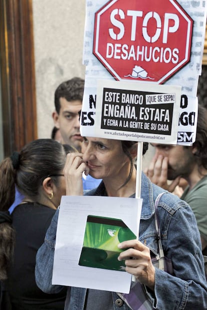 Una mujer porta una pancarta contra los desahucios durante la concentración frente a la sede de Bankia en Madrid.