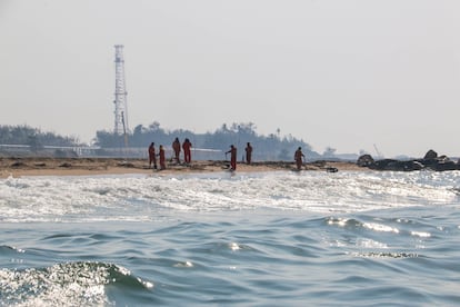 Trabajadores limpian una playa de aceite derramado tras la fuga. 