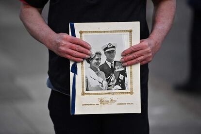 Un ferviente partidario de la familia real británica sostiene una imagen de la reina Isabel II y el duque de Edimburgo frente al castillo de Windsor, tras conocerse el fallecimiento del marido de la reina.