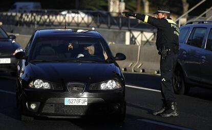 Un conductor con un vehículo con matrícula par recibe las indicaciones de un policía municipal de Madrid en la zona de Moncloa.