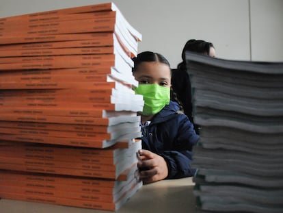 En agosto de 2022, una niña se asoma detrás de una torre de libros de texto de la SEP, en una primaria de la Ciudad de México.
