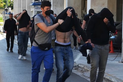 Soccer fans covering their faces, most of them from Croatia, are escorted by police as they leave the Athens Police Headquarters, Greece