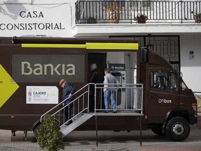 Varios vecinos acuden a la sede bancaria móvil de Bankia, en Corpa (Madrid).