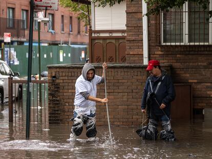 Dos hombres limpian las aguas residuales en una calle inundada durante una fuerte tormenta en Nueva York, el 29 de septiembre de 2023.