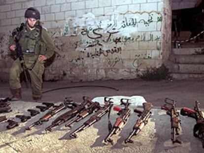 Un soldado israelí, junto a las armas requisadas en Ramala.
