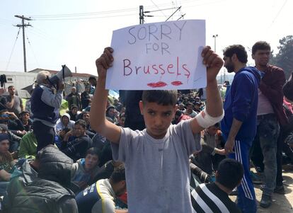 Un nen refugiat sosté un cartell que diu "Ho sento per Brussel·les" durant una protesta contra el tancament de la frontera entre Grècia i Macedònia, a prop de la localitat grega d'Idomeni.