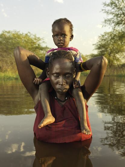 Bol Nual, 26 anos, com sua filha Pouch Deng, 2 anos, a caminho do centro de saúde local para examinar a menina, que está com febre.