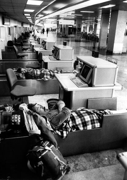 La huegla del 14-D también afectó al aeropuerto de Barajas se paralizó. En la imagen, dos personas duermes en los puestos de facturación de las terminales.