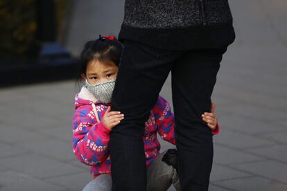 Una niña se protege con una mascarilla de la contaminación ambiental presente en Pekín (China).