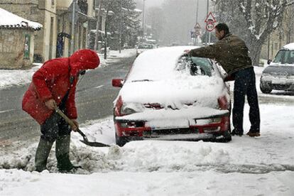 Dos hombres retiran la nieve acumulada ayer sobre las calles y vehículos de la localidad alavesa de Murgia.