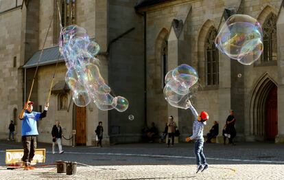 Un niño se divierte con unas pompas de jabón en la plaza Muensterhof de Zúrich (Suiza).