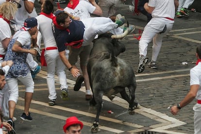 Uno de los seis toros del quinto encierro de los sanfermines ha regresado solo a los corrales de la cuesta de Santo Domingo, donde todavía permanece a la espera de ser trasladado al coso taurino, mientras los otros cinco ya están encerrados en los chiqueros de la plaza. En la imagen, un corredor es cogido por uno de los toros.