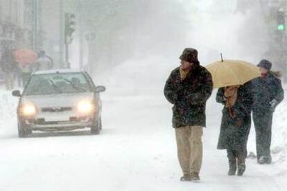 Un grupo de personas camina por la avenida principal de la localidad cántabra de Reinosa, completamente cubierta por la nieve.