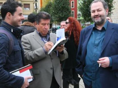 Julio García Llopis firma un libro a un lector, junto a Juan Bas (a la derecha) en el 'bookcrossing' organizado por Federiko Ezkerra.