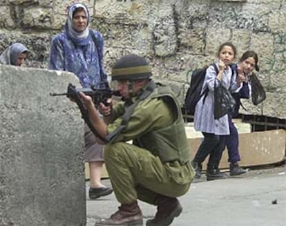 Unas niñas se tapan los oídos mientras un soldado israelí dispara contra los palestinos en Hebron.