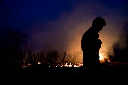 Un hombre parado frente a uno de los incendios.