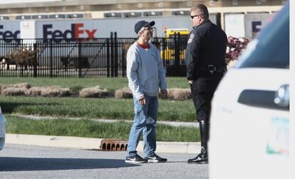 Un oficial habla con un hombre mientras custodia la entrada a la instalación de FedEx, este viernes.