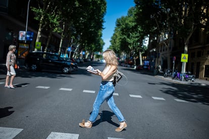 La líder de Sumar, Yolanda Díaz, lee un periódico mientras cruza la calle Ríos Rosas, en Madrid, este domingo.