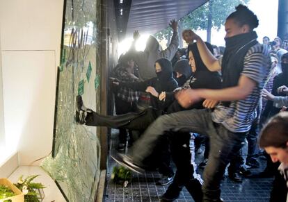 Un grupo de manifestantes rompe un escaparate de unos grandes almacenes del centro de Barcelona.