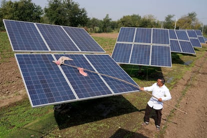 Farmer Pravinbhai Parmar cleans a solar panel installed at a farm in Dhundi village of Kheda district in western Indian Gujarat state, India