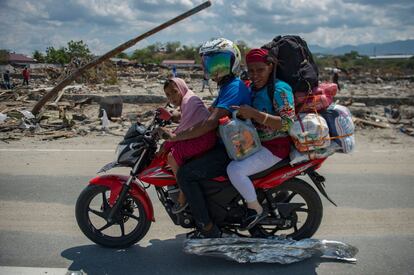 Una familia afectada por la catástrofe natural en Indonesia, traslada lo que queda de sus pertenencias en moto, en el área devastada de Palu, el 3 de octubre de 2018.