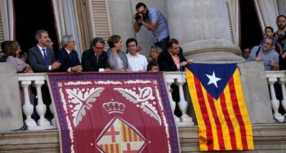 Alfred Bosch, conseller d'Esquerra Republicana, ajuda a lligar l'estelada perquè la bandera se sostingui a la balconada. L'escena té lloc sota l'atenta mirada de l'alcaldessa de Barcelona, Ada Colau, i mentre altres personalitats com el presidente de la Generalitat, Artur Mas, mira la gent reunida a la plaça de Sant Jaume.