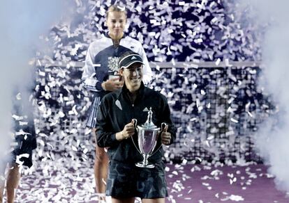 Garbiñe Muguruza holds her trophy, while Anett Kontaveit stands with the runner-up prize.