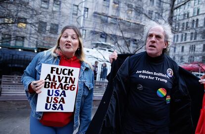 Seguidores de Donald Trump llevaban el lunes pancartas con insultos al fiscal Alvin Bragg y al presidente Biden, afuera de la corte criminal de Manhattan.